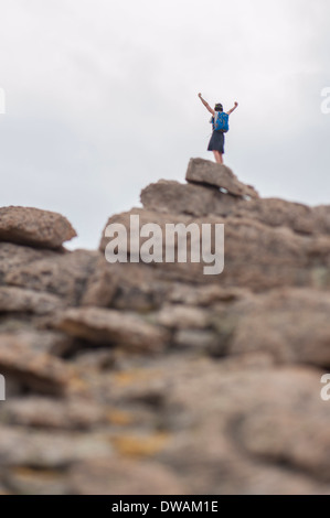 Tilt Shift foto di un escursionista con braccia sollevate al di sopra della cima di una montagna. Foto Stock