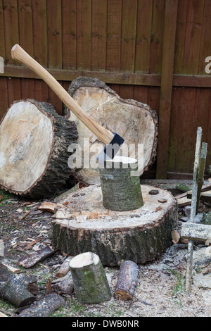 Un'ascia in un pezzo di legno su un blocco di taglio per la produzione di legna da ardere, Inghilterra, Regno Unito Foto Stock