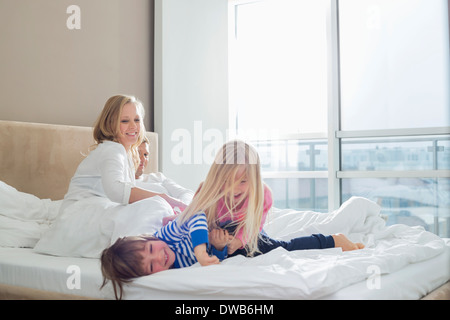 Genitori felici guardando bambini allegri in camera da letto Foto Stock