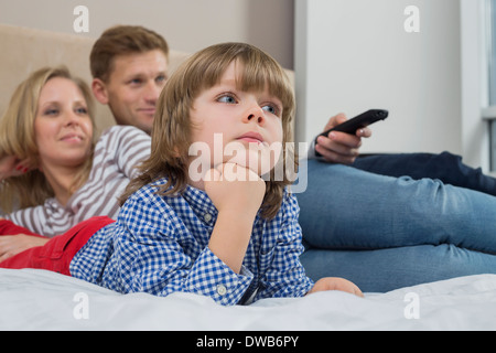 Famiglia a guardare la TV in camera da letto Foto Stock