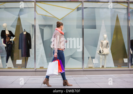 Colpo di profilo di giovane donna con le borse della spesa guardando la finestra di visualizzazione Foto Stock