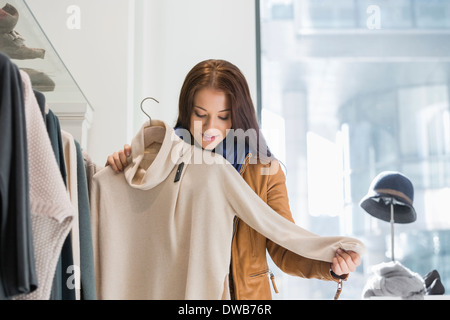 Giovane donna scegliendo un maglione in negozio Foto Stock