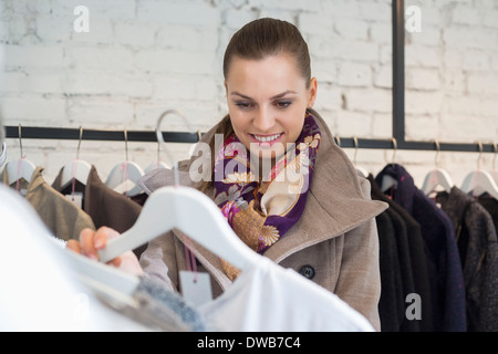 Sorridente giovane donna scegliendo un maglione in negozio Foto Stock