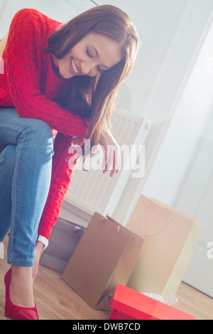 Felice giovane donna cercando di calzature in negozio Foto Stock