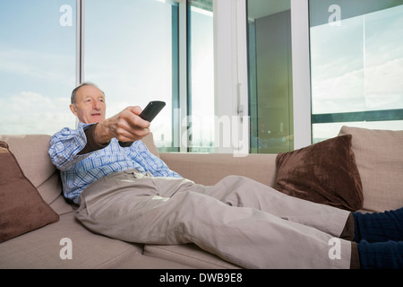Senior uomo guarda la TV sul divano di casa Foto Stock