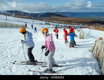 Bambini con lezioni di sci su piste baby in Cairngorm Mountain Ski Center, da Aviemore, Highlands scozzesi, Scotland Regno Unito Foto Stock