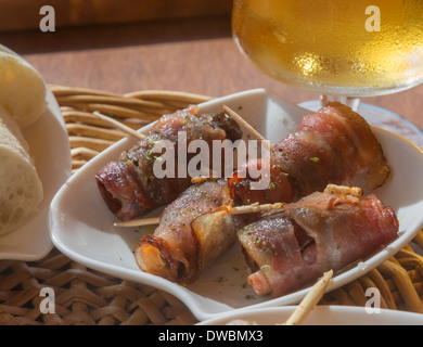 Data di pancetta tapas. Le tapas con date laminati in pancetta e una birra su di un ristorante tavolo. Maiorca, isole Baleari, Spagna. Foto Stock