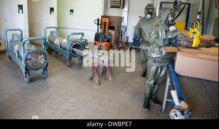 Munster, Germania. 5 Mar 2014. Un dipendente di GEKA, la proprietà del governo azienda specializzata nello smaltimento delle armi chimiche, indossa una tuta protettiva come egli carica un manichino granade per ulteriore elaborazione durante una presentazione per la stampa nei locali dell'azienda in Munster, Germania, 5 marzo 2014. La GEKA (Gesellschaft zur Entsorgung von chemischen Kampfstoffen und Ruestungsaltlasten/GEKA) è la sola azienda in Germania che è coinvolto nello smaltimento delle armi chimiche da parte della Siria. Foto: Philipp Schulze/dpa/Alamy Live News Foto Stock