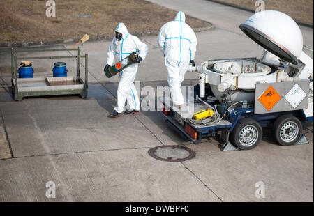 Munster, Germania. 5 Mar 2014. Due dipendenti di GEKA, la proprietà del governo azienda specializzata nello smaltimento delle armi chimiche, indossare tute di protezione come essi lo smaltimento delle cartucce di dummy contenenti agenti di guerra chimica durante la simulazione di una procedura per i supporti sulla sede della società in Munster, Germania, 5 marzo 2014. La GEKA (Gesellschaft zur Entsorgung von chemischen Kampfstoffen und Ruestungsaltlasten/GEKA) è la sola azienda in Germania che è coinvolto nello smaltimento delle armi chimiche da parte della Siria. Foto: Philipp Schulze/dpa/Alamy Live News Foto Stock