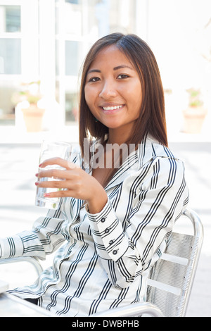 Ritratto di un sorridente ragazza asiatica di bere un bicchiere di acqua Foto Stock