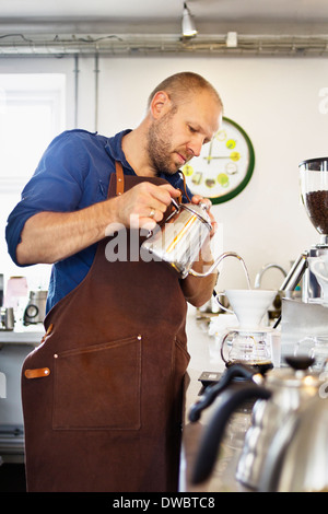 Barista maschio versando acqua bollente in un filtro del caffè Foto Stock