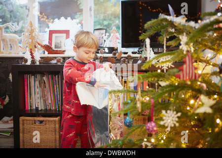 Ragazzo giovane disimballaggio regalo a Natale Foto Stock