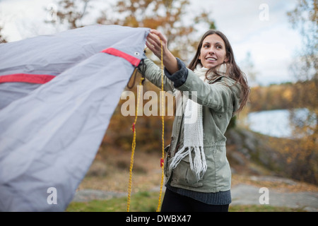 Giovane donna impostazione tenda mentre guarda lontano nella foresta Foto Stock