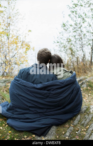 Vista posteriore del giovane avvolto in una coperta a foresta Foto Stock