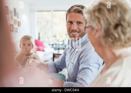 Uomo sorridente guardando alla madre durante il pranzo Foto Stock