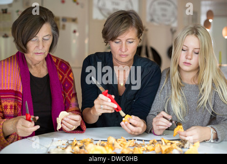 Tre femmine di generazione di pulizia fungo chanterelle a casa Foto Stock