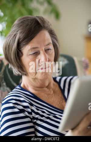 Donna senior con tavoletta digitale in casa Foto Stock