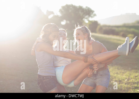 Due giovani femmine ingannare intorno cercando di portare un amico Foto Stock