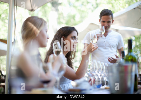 Giovani amici di degustazione e guardando il vino al bar del vigneto Foto Stock