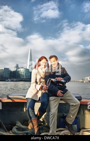 Coppia romantica sul Tamigi la condivisione di barca champagne rosato, London, Regno Unito Foto Stock