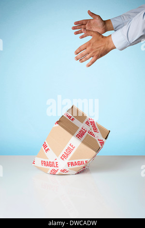 Studio shot di mani la caduta di scatola di cartone contrassegnato fragile Foto Stock