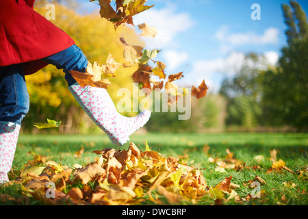 Ritagliato colpo di donna matura calci Foglie di autunno nel parco Foto Stock