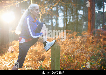 Donna matura allungamento della gamba sul palo di legno Foto Stock