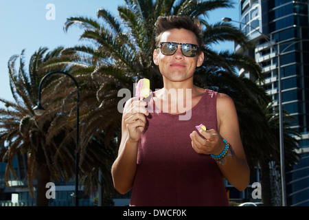 Giovane uomo godendo di ghiaccio per lecca-lecca, Port Melbourne, Melbourne, Australia Foto Stock