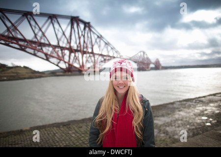 Una giovane donna pone di fronte al Ponte di Forth Rail in Queensferry, nei pressi di Edimburgo, Scozia Foto Stock