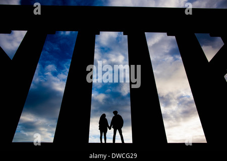 Una coppia giovane tenere le mani al Monumento Nazionale a Calton Hill a Edimburgo, Scozia Foto Stock