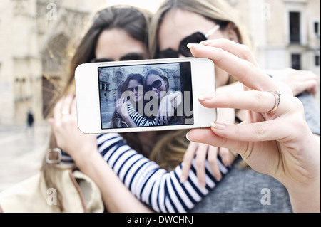 Due giovani amici di sesso femminile prendendo un autoritratto, Valencia, Spagna Foto Stock