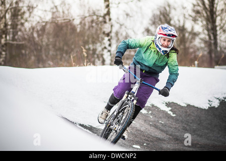 Giovani femmine mountain biker in sella a neve Foto Stock