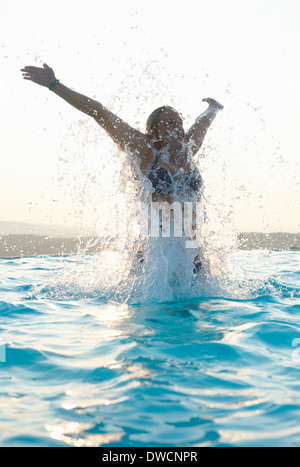 Giovane donna con braccia spruzzi in piscina Foto Stock