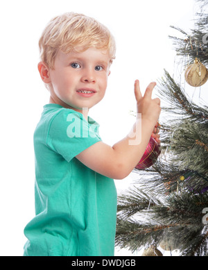 Preschooler sorridente alla telecamera la decorazione di un albero di Natale. Foto Stock