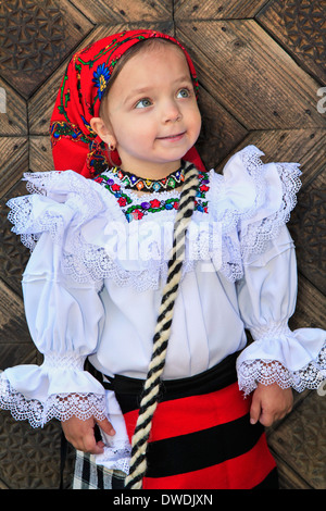 Bambina rumena che indossano abiti tradizionali e tradizionali in legno sullo sfondo della porta Foto Stock