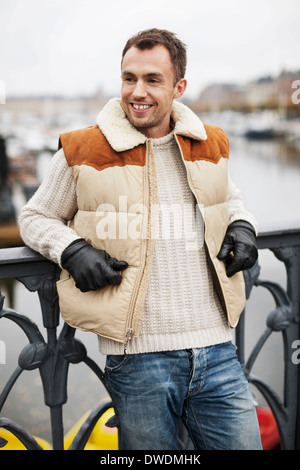 Felice l'uomo appoggiato sulla ringhiera all'aperto Foto Stock