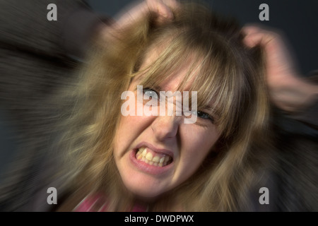 Un molto arrabbiato giovane donna strappando i suoi capelli. Foto Stock