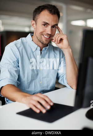 Ritratto di imprenditore sorridente utilizzando computer in ufficio Foto Stock