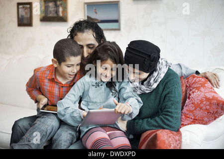 La famiglia musulmana con tavoletta digitale insieme in salotto Foto Stock