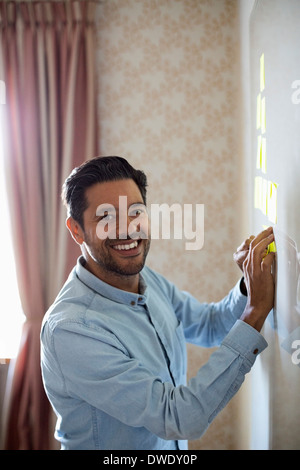 Ritratto di happy businessman incollaggio note adesive su whiteboard Foto Stock