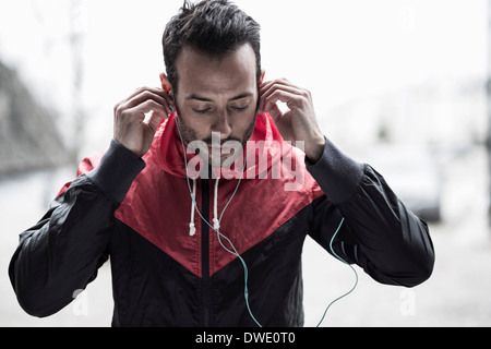 Uomo sportivo in giacca cuffie di regolazione Foto Stock