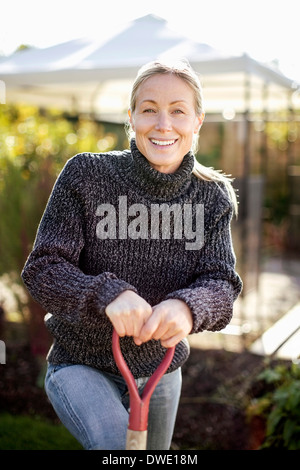 Ritratto di donna sorridente tenendo la pala in giardino Foto Stock