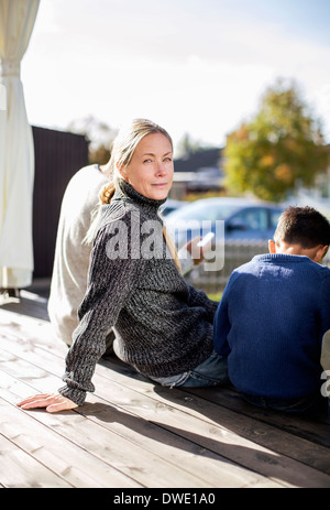 Ritratto di donna matura seduta con la famiglia in cantiere Foto Stock