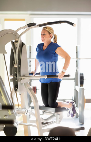 Senior donna esercita sul pull-up assistere la macchina a palestra Foto Stock