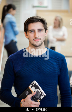 Ritratto di fiducia studente maschio azienda prenota in aula Foto Stock