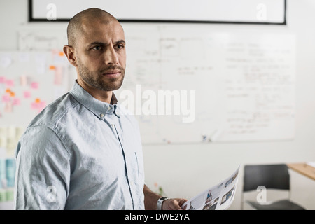 Considerato imprenditore tenendo i documenti in ufficio creativo Foto Stock