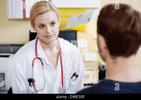 Giovani donne medico con il paziente di sesso maschile in clinica Foto Stock