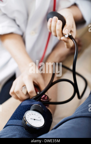 Immagine ritagliata del medico donna facendo pressione del sangue del paziente presso la clinica Foto Stock