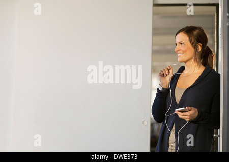 Felice giovane imprenditrice parla attraverso le cuffie in ufficio Foto Stock