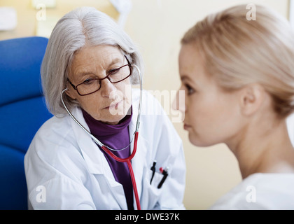 Senior medico donna esame paziente in clinica Foto Stock